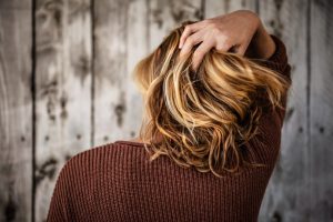 blonde woman with back to camera, playing with hair