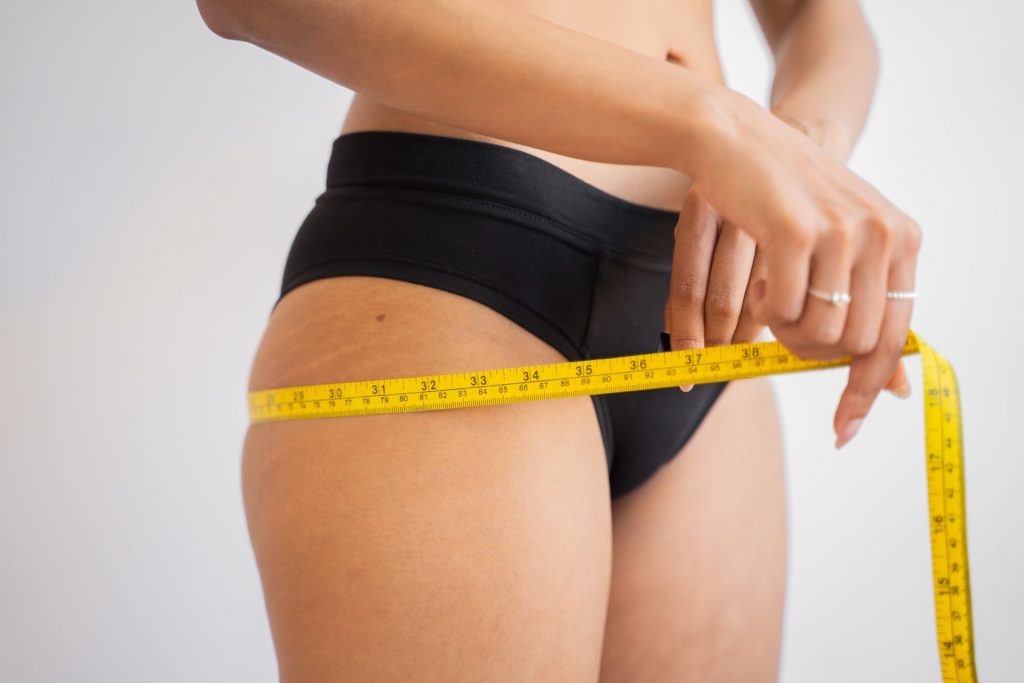 tape measure, measuring hips, woman in black underwear up close